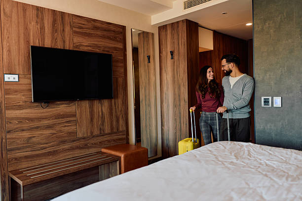 istock Couple arriving at hotel room pulling luggage 2245303443