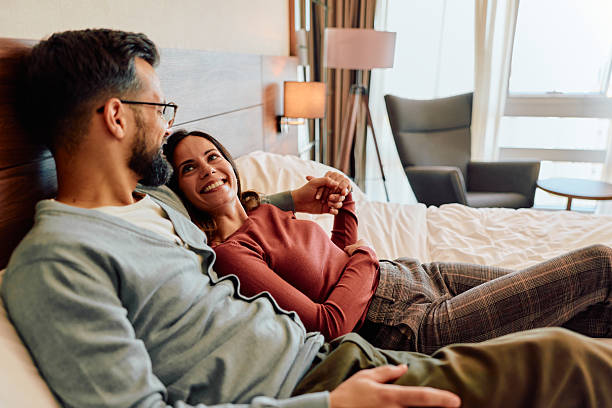 istock Couple relaxing in bed holding hands looking happy 2245303567