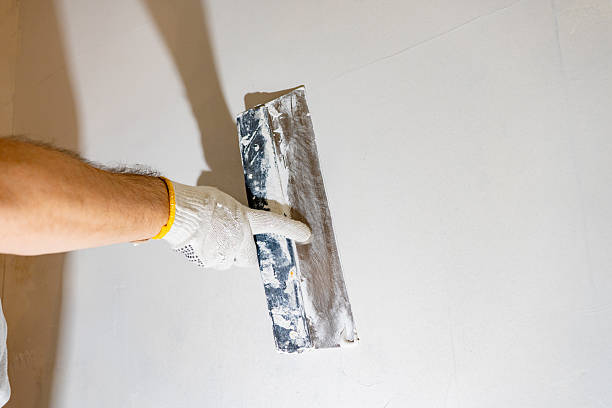 istock Gloved worker actively spreads white spackling compound with a finishing tool, preparing the textured wall for a final coat. 2245303667