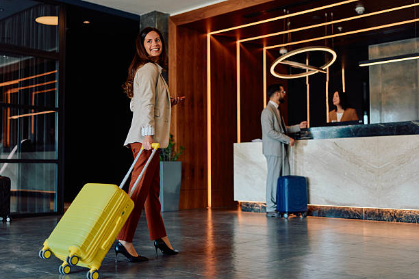 istock Stylish businesswoman pulling luggage in hotel lobby 2245303709