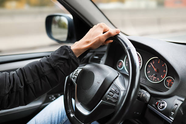 istock A man drives a car with a modern black leather interior. An autumn cityscape is visible outside the window. 2245306050