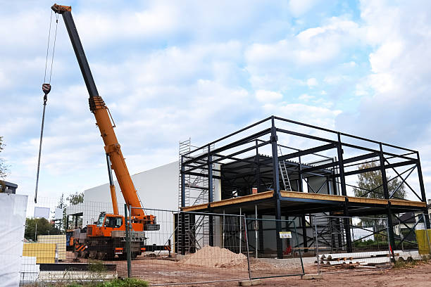 istock A truck crane operates at a construction site with a new building structure. The area is surrounded by fencing and materials are scattered around. 2245306172