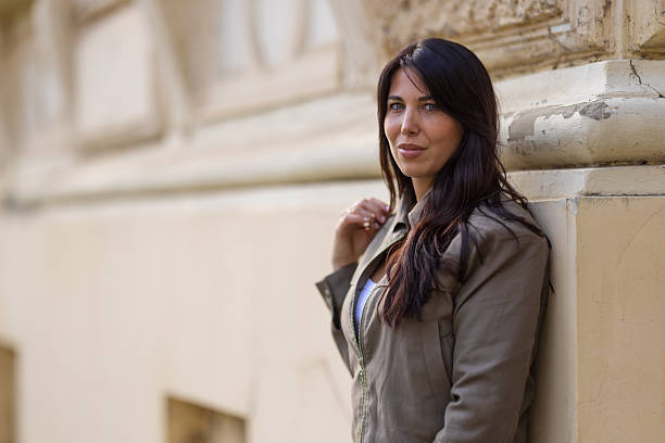 istock portrait of a beautiful brunette leaning against a building 2245306754