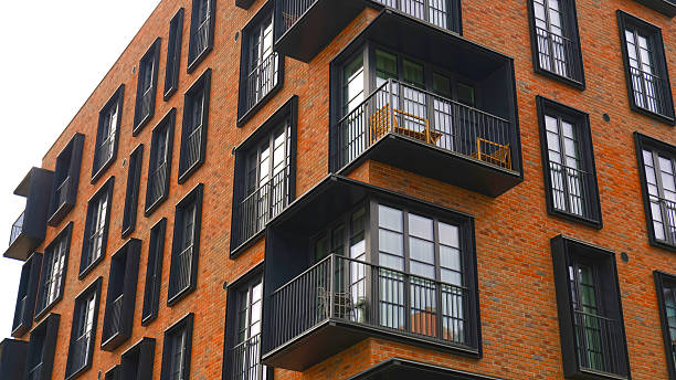 istock Contemporary apartment facade with warm brick cladding and black framed French windows features repeating balconies. Real estate, urban living, and property marketing. 2245306860