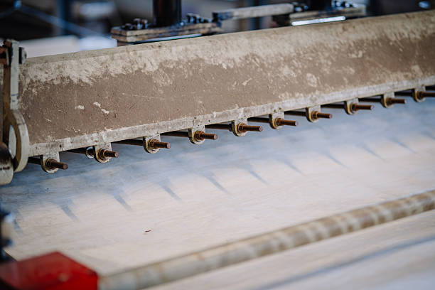 istock Close-up of industrial woodworking machine with multiple metal pins pressing or processing thin veneer sheets on a production line in a factory setting. 2245307090