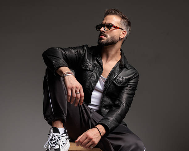 istock confident cool man with sunglasses looking to side and sitting with elbow on knee 2245307676