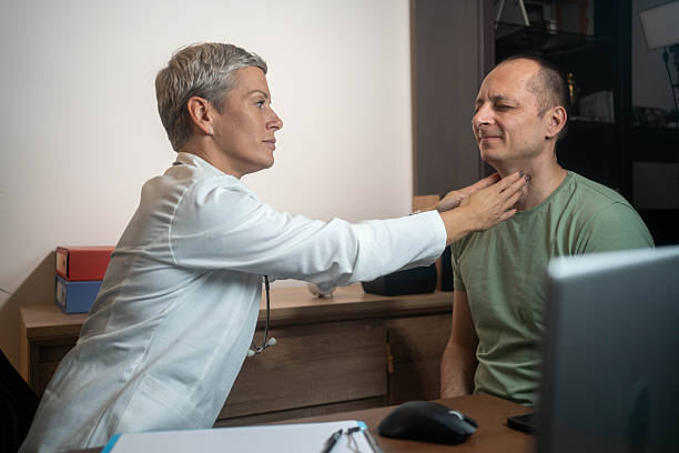 istock Endocrinologist examining male patient throat for thyroid checkup. 2245308633