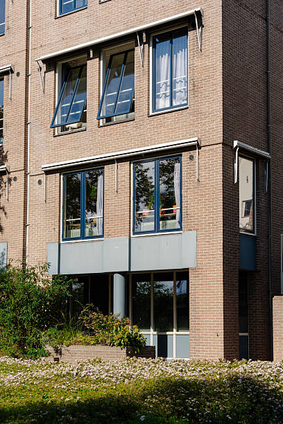 istock Brick building with open windows and flowerbeds, showcasing simple architecture and natural light. 2245309555