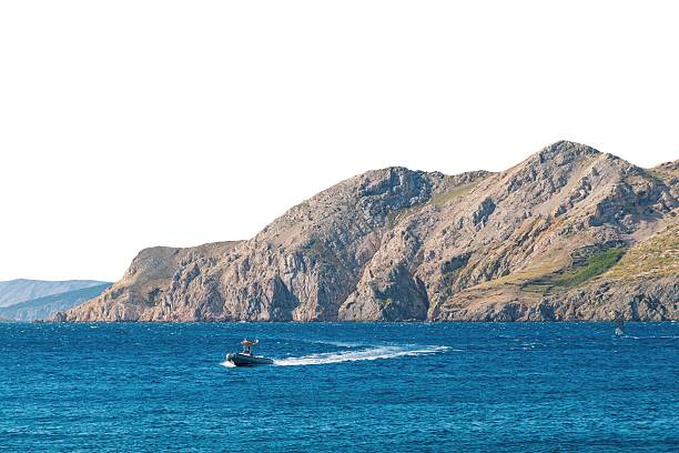 Speedboat on vibrant blue sea near rocky coastal cliffs. Isolated object on white background.
