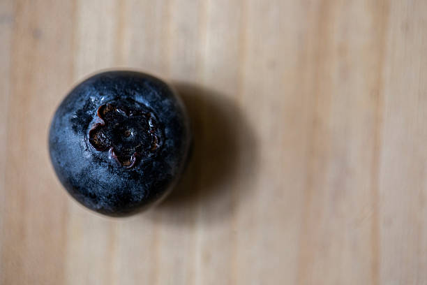 Single blueberry on a wooden ground.