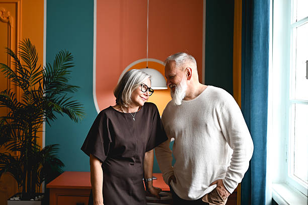 Senior couple looking at each other gently smiling at modern home