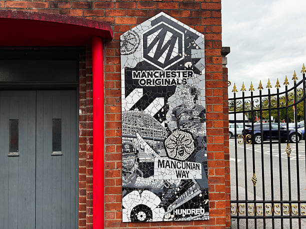 Manchester, UK - September 30, 2025: Colorful Mancunian Way mosaic panel on a brick facade near a gated area in Manchester, UK.