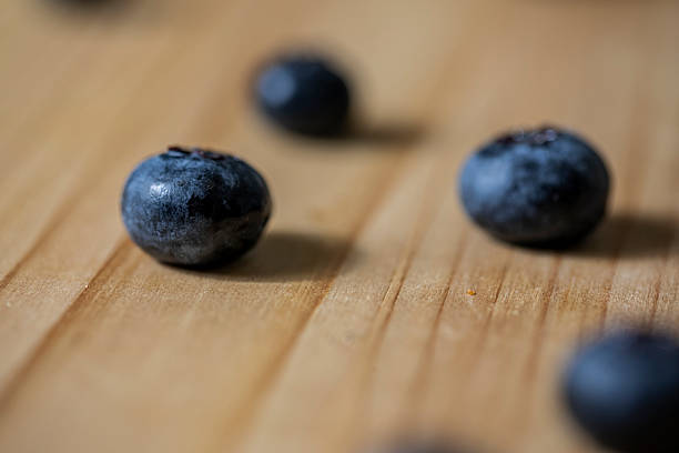 Close-up of fresh blueberries on a plate and a glass of blueberry juice on a wooden table.