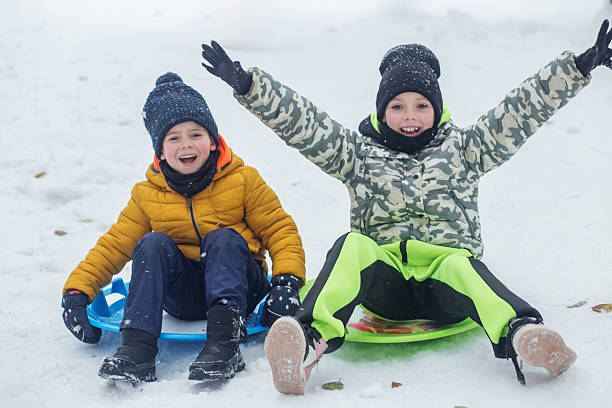 istock Two happy kids sledding in winter snow 2245319016