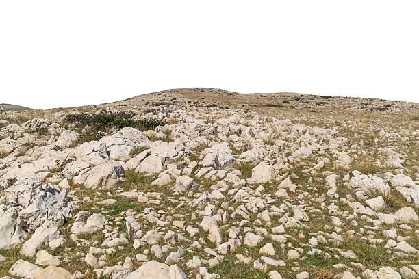 Rocky terrain with sparse vegetation on hilltop. Isolated object on white background.