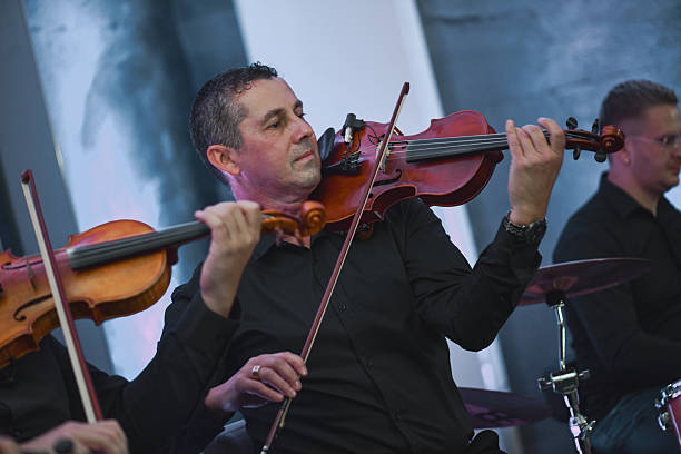 istock Violinist Smiling During a Live Music Session With Ensemble and Bow in Hand 2245319404