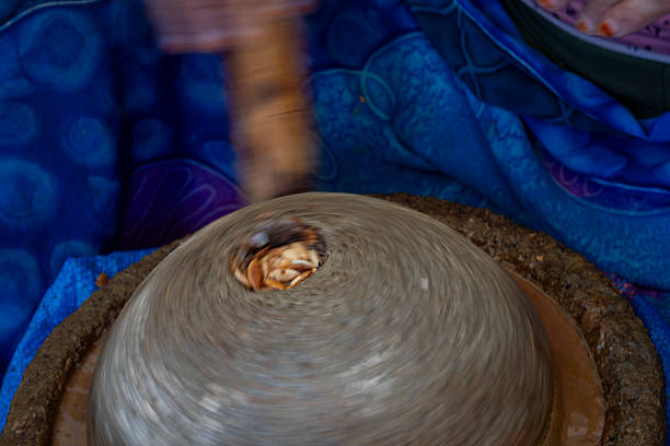 Argan oil extraction by traditional stone handmill. A Berber woman extracts argan oil, Essaouira, Morocco, North Africa. Closeup, movement.