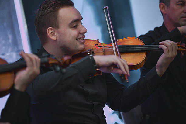 istock Violinist Smiling During a Live Music Session With Ensemble and Bow in Hand 2245319612
