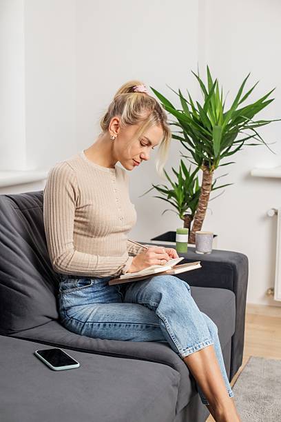istock Woman journaling at home on cozy couch 2245320072