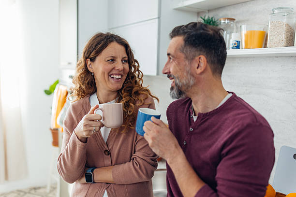 istock Couple Smiling with Coffee in Cozy Kitchen Setting 2245326114