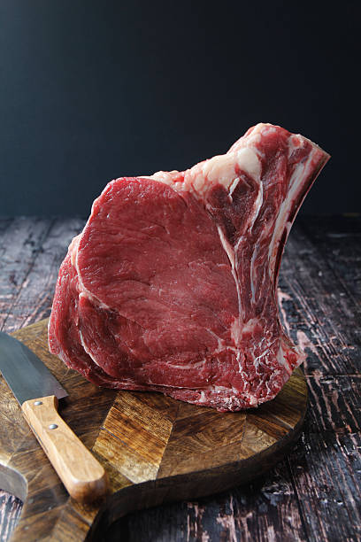 Raw beef rib steak on wooden board