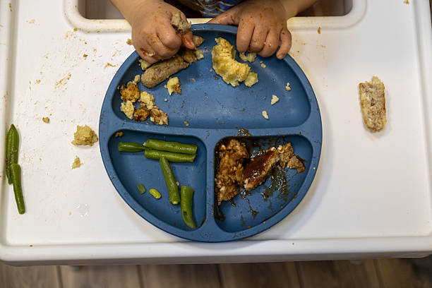 Kid's meal - fried chicken strips, french fries, salad and ketchup. Colorful dinner - plate in child's hands on white wooden table. Captured from above (top view, flat lay).
