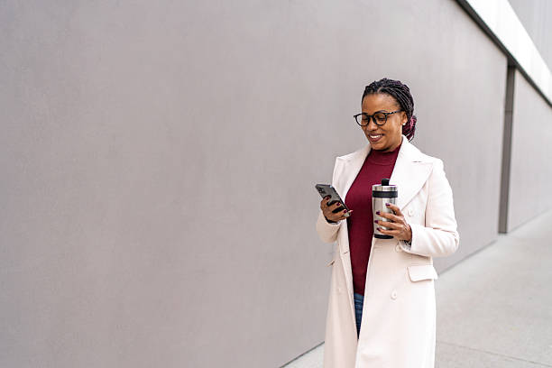 istock Woman walking city checking phone and drinking coffee 2245329080