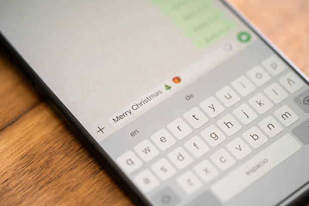 Close-up view of a cell phone screen displaying a text message in a conversation with an emoji that says: Merry Christmas