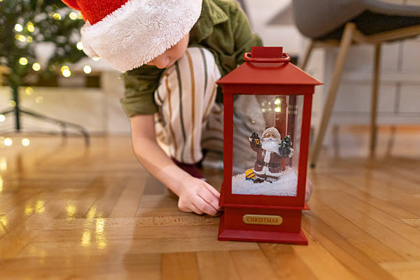 istock Child with Santa hat arranging a red Christmas lantern on the floor. 2245332233