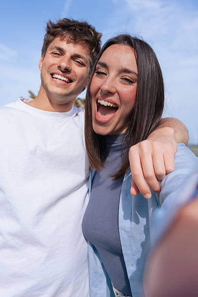 istock Happy young couple taking cheerful selfie outdoors on sunny day, vertical shot. 2245334687