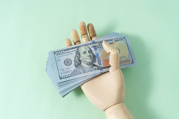 istock Wooden hand model and dollar banknote 2245336899