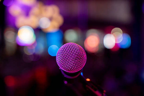 istock Close up of microphone in bar with blurred crowd in background. 2245337117