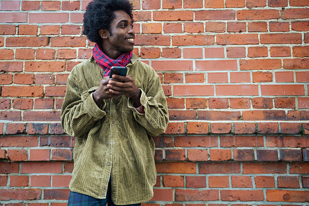 istock Stylish Man Talking on Smartphone by Brick Wall 2245337936