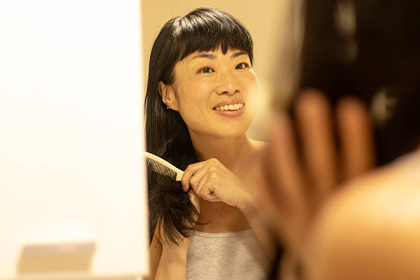 istock Asian woman combing hair in bathroom during morning routine 2245341470