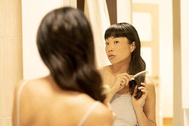 istock Asian woman combing hair reflecting in mirror 2245341516