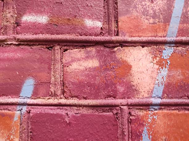 Close-up of a brick wall covered in vibrant graffiti. Various shades of red, pink, and orange create an abstract pattern.
