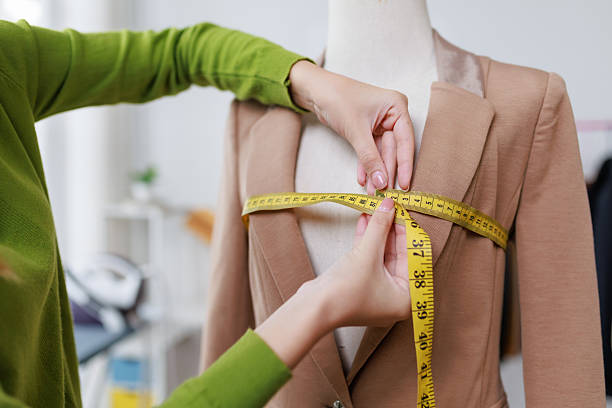 istock Skilled seamstress measuring tailored jacket chest area on mannequin, ensuring precise professional garment fitting in cozy atelier workspace 2245342312