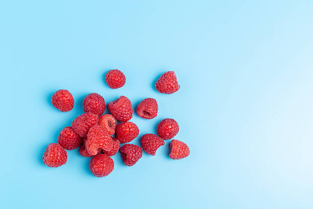 istock Healthy summer berries, a small pile of raspberries on a smooth blue surface 2245343076