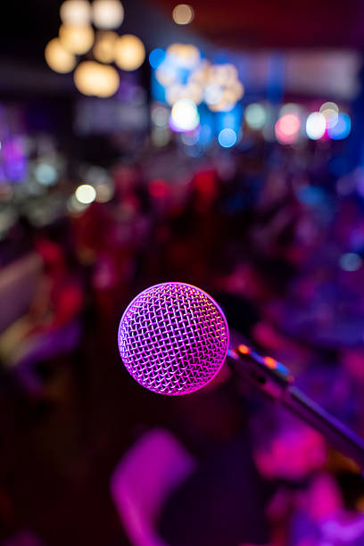 istock Close up of microphone in bar with blurred crowd in background. 2245345729
