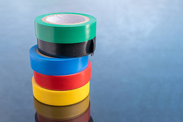 istock Rolls of colorful electrical tape stacked vertically on a dark, reflective surface, representing safety, repair, or organization 2245345766