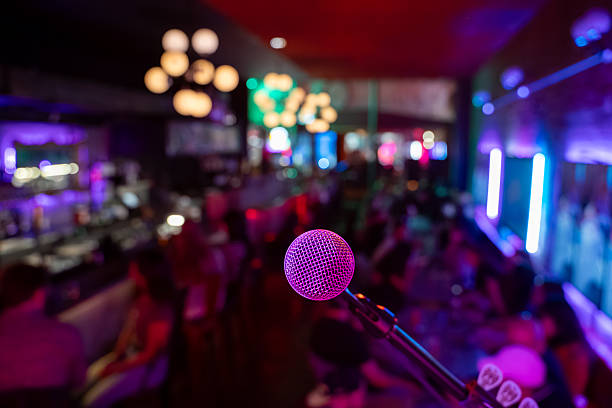 istock Close up of microphone in bar with blurred crowd in background. 2245345876