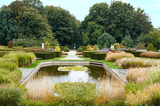istock Serene garden landscape featuring a tranquil pond surrounded by lush greenery, colorful flowers, and neatly trimmed hedges, creating a peaceful outdoor retreat for relaxation and reflection 2245346228