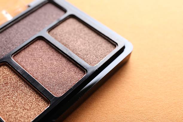 istock Eyeshadow palette on orange background, closeup. Makeup cosmetics 2245347251