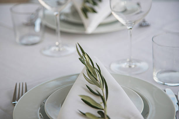 istock Elegant outdoor table set for two, featuring white plates, glassware, and a simple olive branch on each napkin. Focus on lifestyle, minimalism, and detail. 2245349899