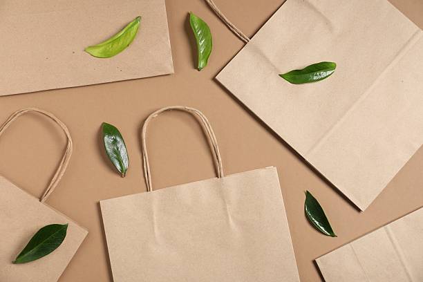 istock Eco friendly packaging. Paper bags and leaves on light brown background, flat lay 2245353409