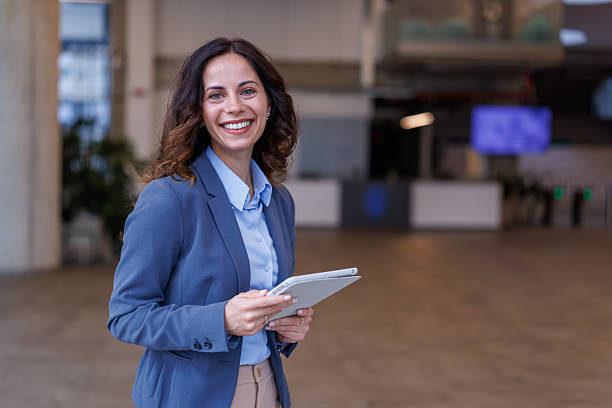 istock Businesswoman holding digital tablet smiling in modern office building 2245358317