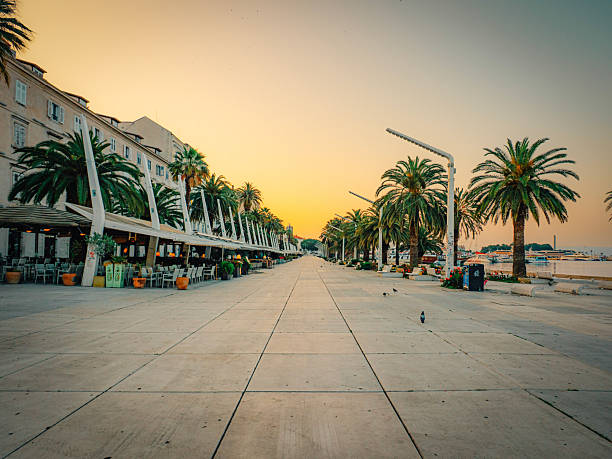 Sunrise on Split’s palm-lined Riva promenade, quiet terraces and Adriatic glow beside Diocletian’s Palace—a serene summer morning in Dalmatia, Croatia, Europe.