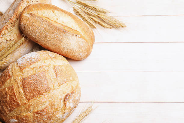 istock Different types of bread and wheat spikes on wooden table, flat lay. Space for text 2245363053