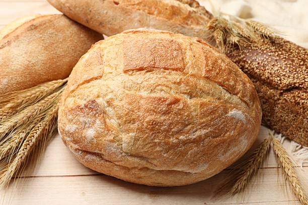 istock Different types of bread and wheat spikes on wooden table, closeup 2245365687