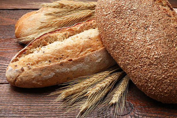 istock Different types of bread and wheat spikes on wooden table, closeup 2245365689